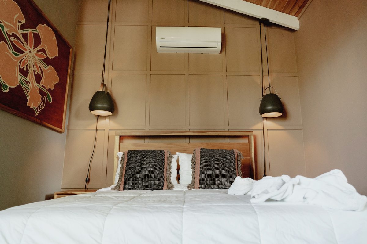 A bright, cozy queen room with a black iron bed, white linens and a built-in closet
