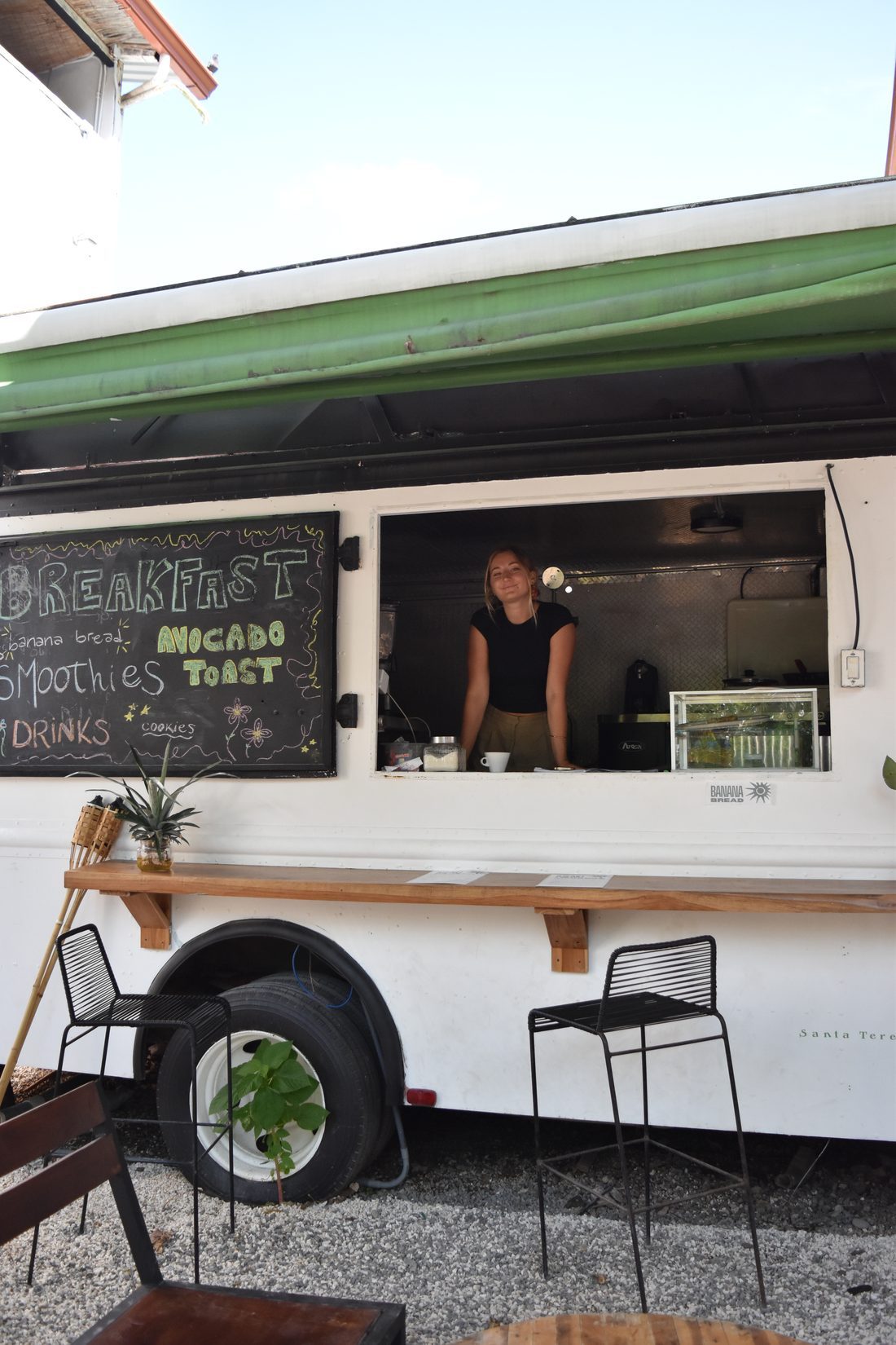 The Armonia food truck with a chalkboard menu and a server at the window, bar stools alongside