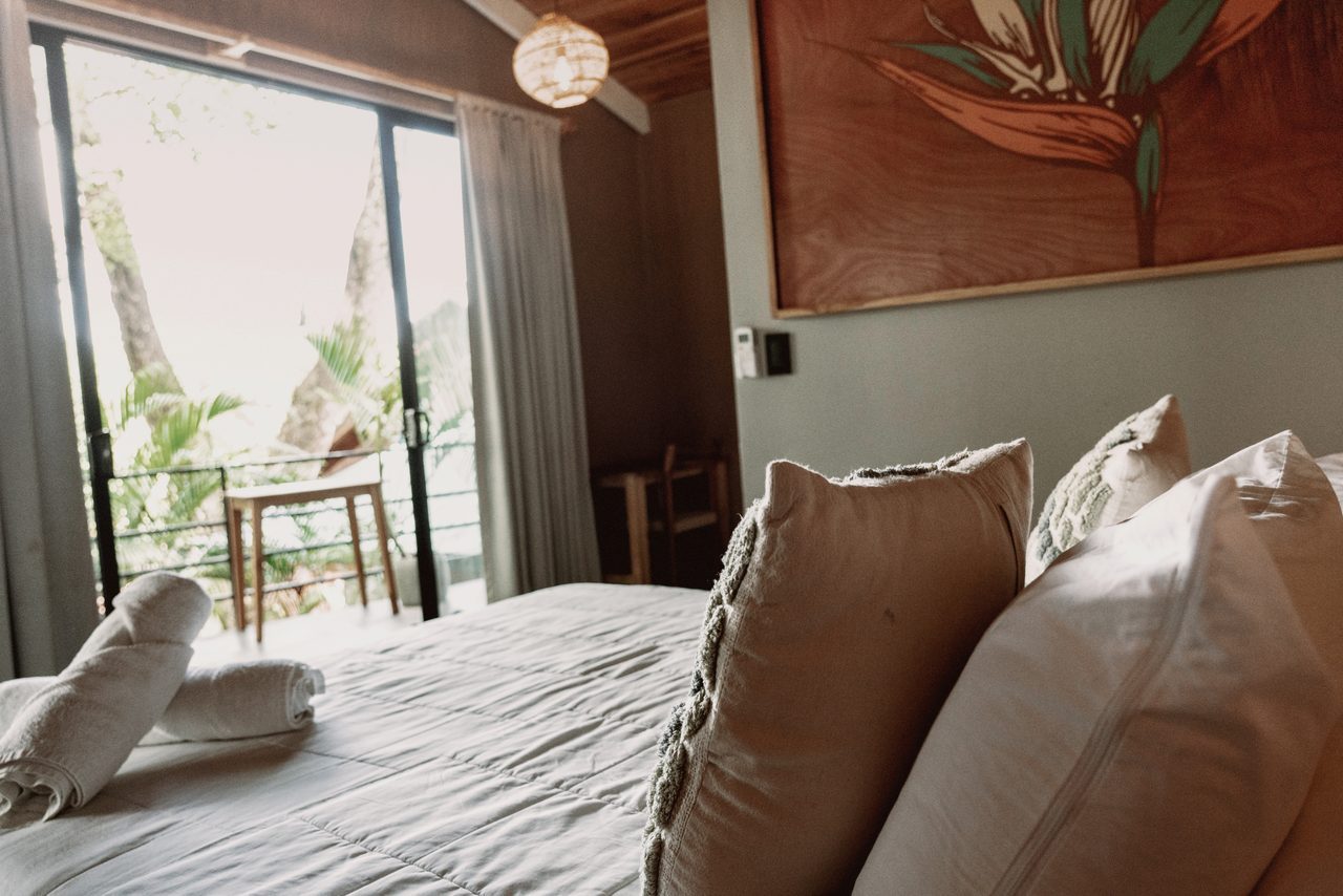 A serene queen bedroom with a botanical headboard and a private balcony opening to the jungle